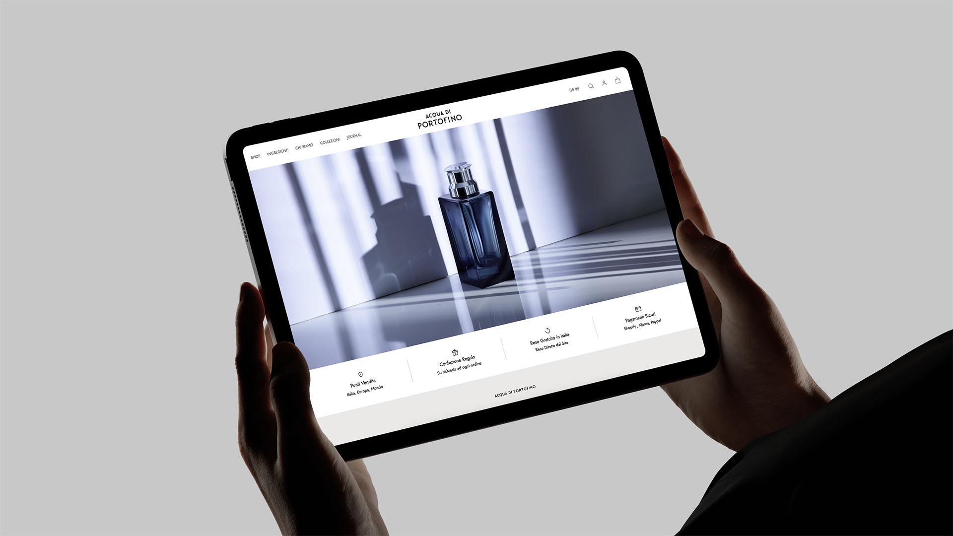 Hands holding an iPad displaying the luxury e-commerce online store layout for Acqua di Portofino.