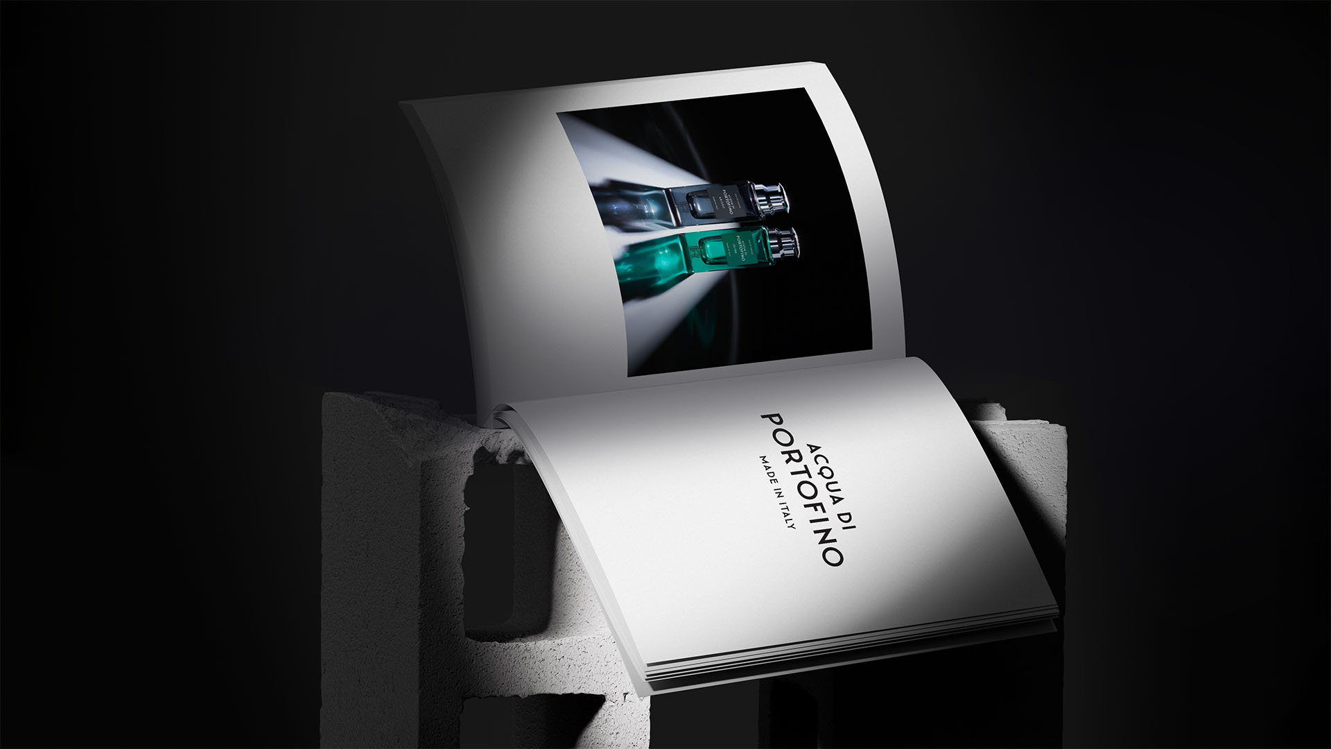 Open printed brand publication spread resting on a cinder block featuring luxury perfume photography.