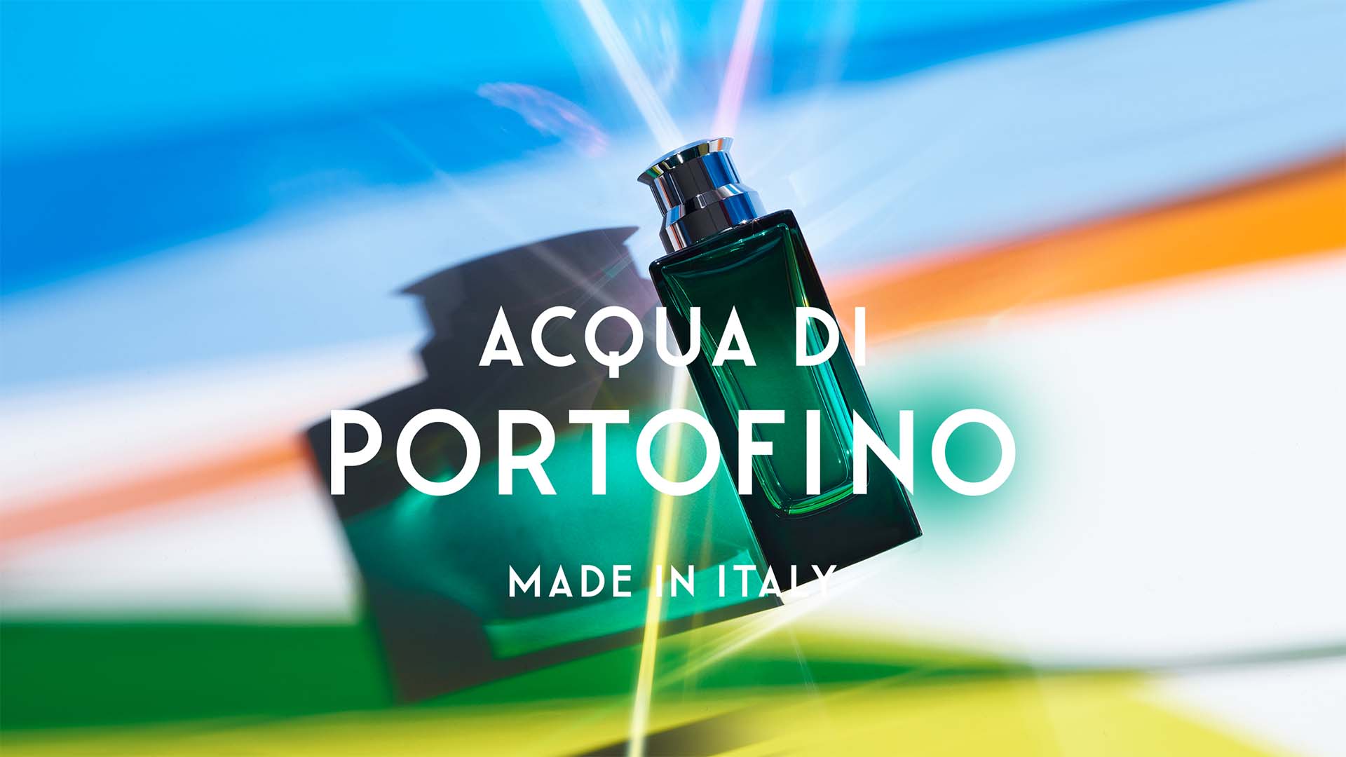 Green glass fragrance bottle shot against vibrant prism light refractions for Italian Riviera perfume house.