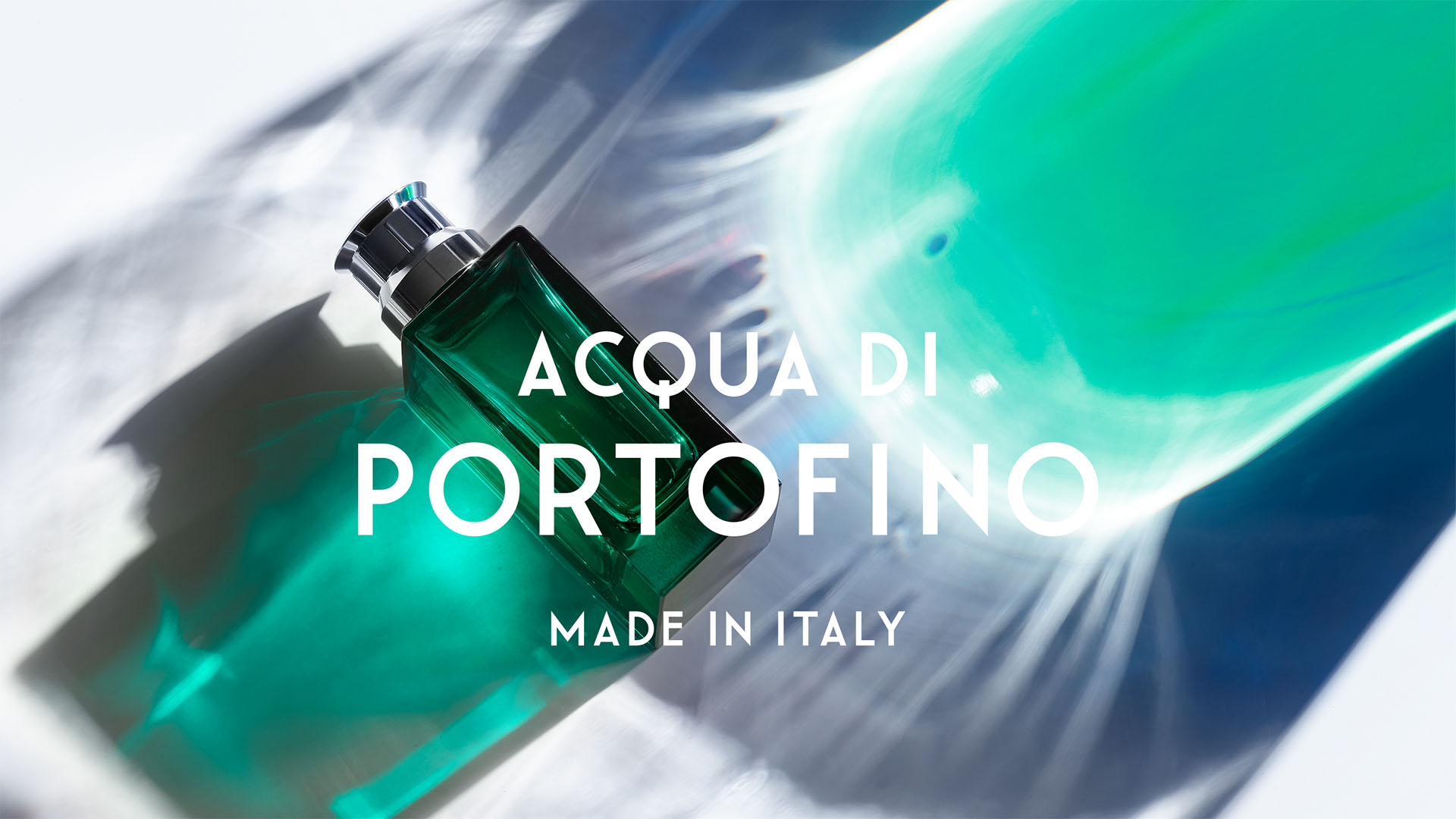 Emerald green glass perfume bottle resting on a light-refracting Mediterranean water background for Acqua di Portofino.