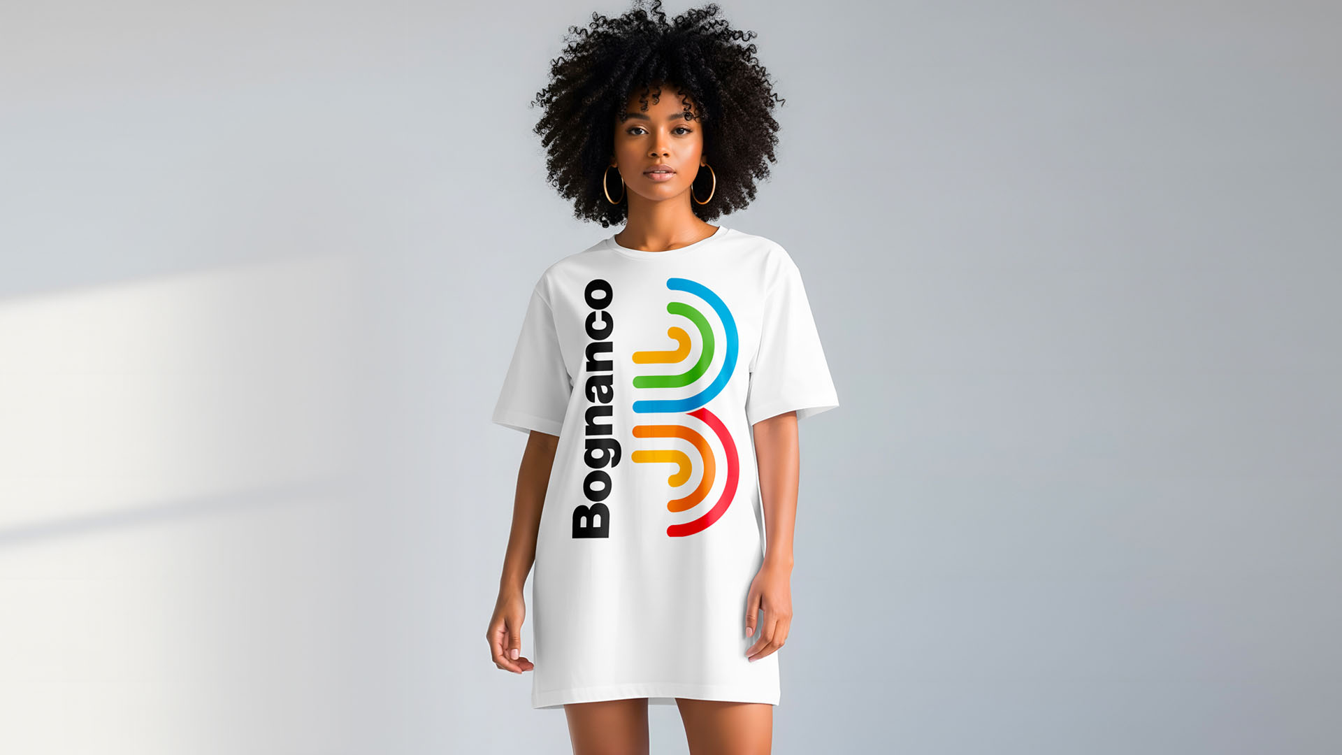 Female model wearing an oversized white t-shirt dress printed with bold Bognanco logo and fountain icon.