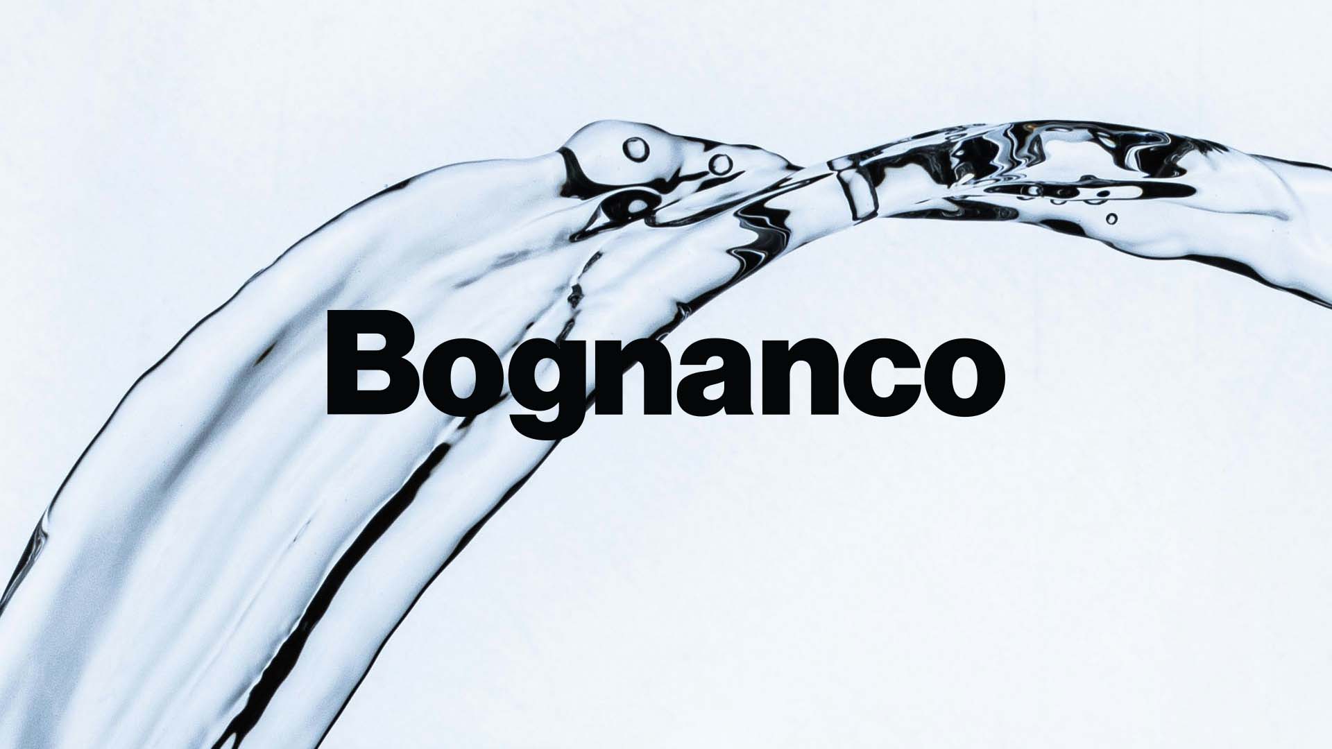 Dynamic macro shot of an arching clear mineral water stream flowing over the bold Bognanco logotype.