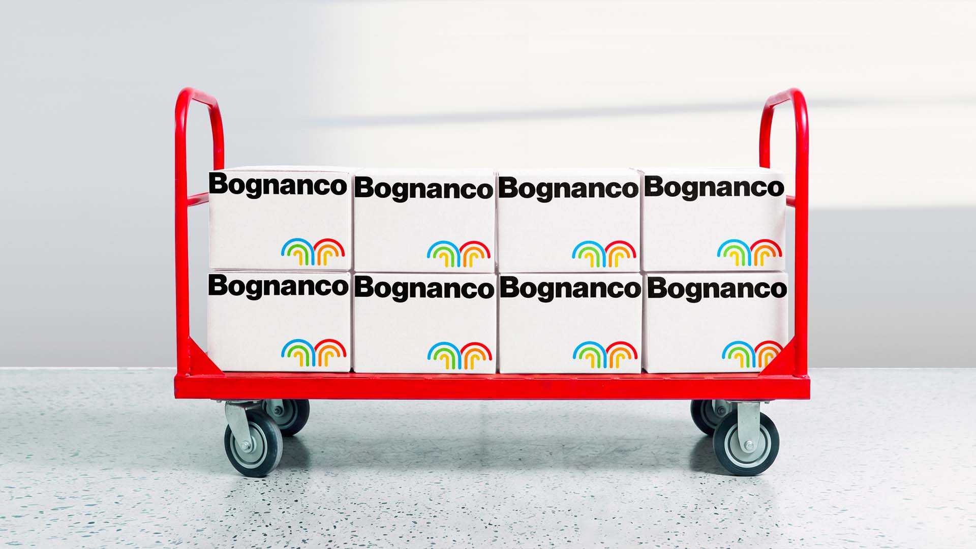 Red industrial hand trolley loaded with eight white branded corrugated Bognanco shipping boxes.